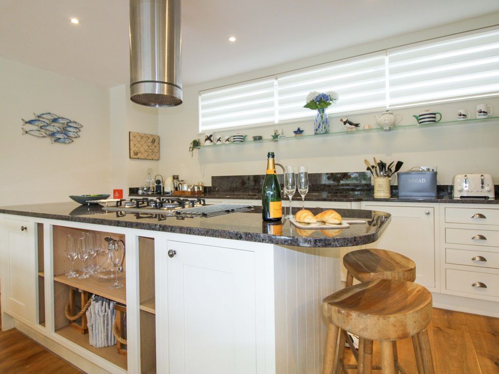 A kitchen with a gas stove and bar stools at Villa 1, Estura Salcombe
