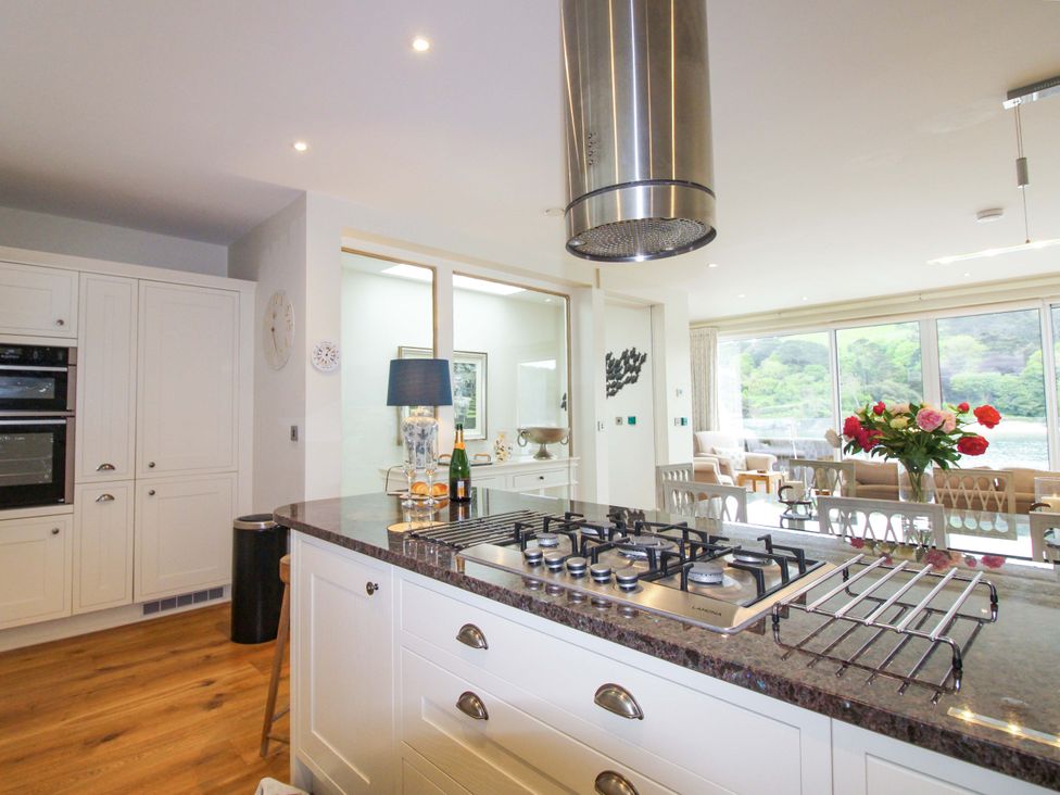 A kitchen with a gas stove and dining chairs at Villa 1, Estura Salcombe