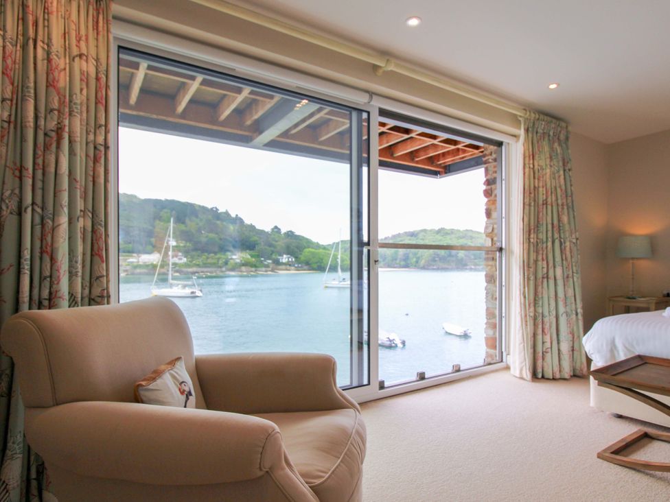 A bedroom with an armchair and a view of the water at Villa 1, Estura, Salcombe