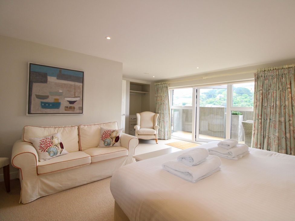 A bedroom with a sofa and towels on the bed at Villa 1, Estura in Salcombe