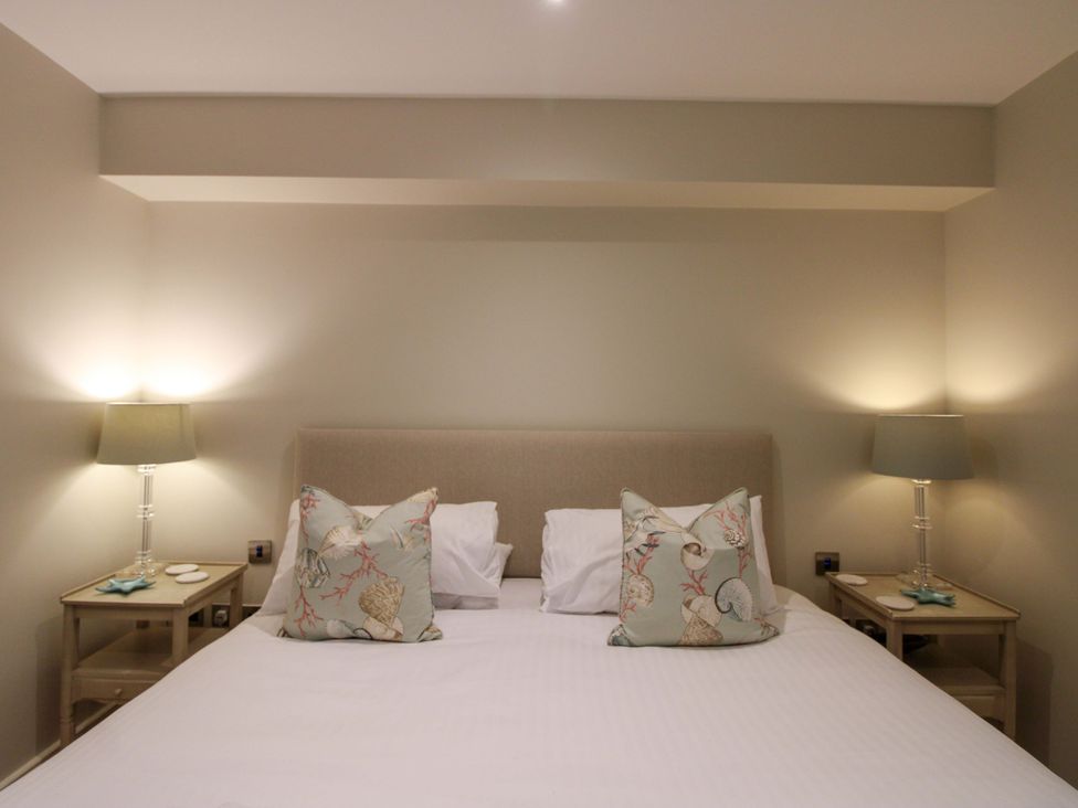 A bedroom with a bed and bedside lamps at Villa 1, Estura Salcombe