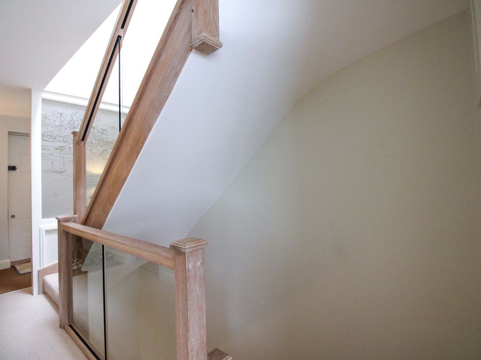 A staircase with a wooden handrail and wall paneling at Villa 1, Estura Salcombe