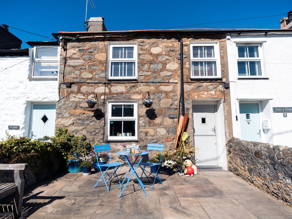 An outdoor patio with blue furniture and plants at Gerallt in Morfa Nefyn