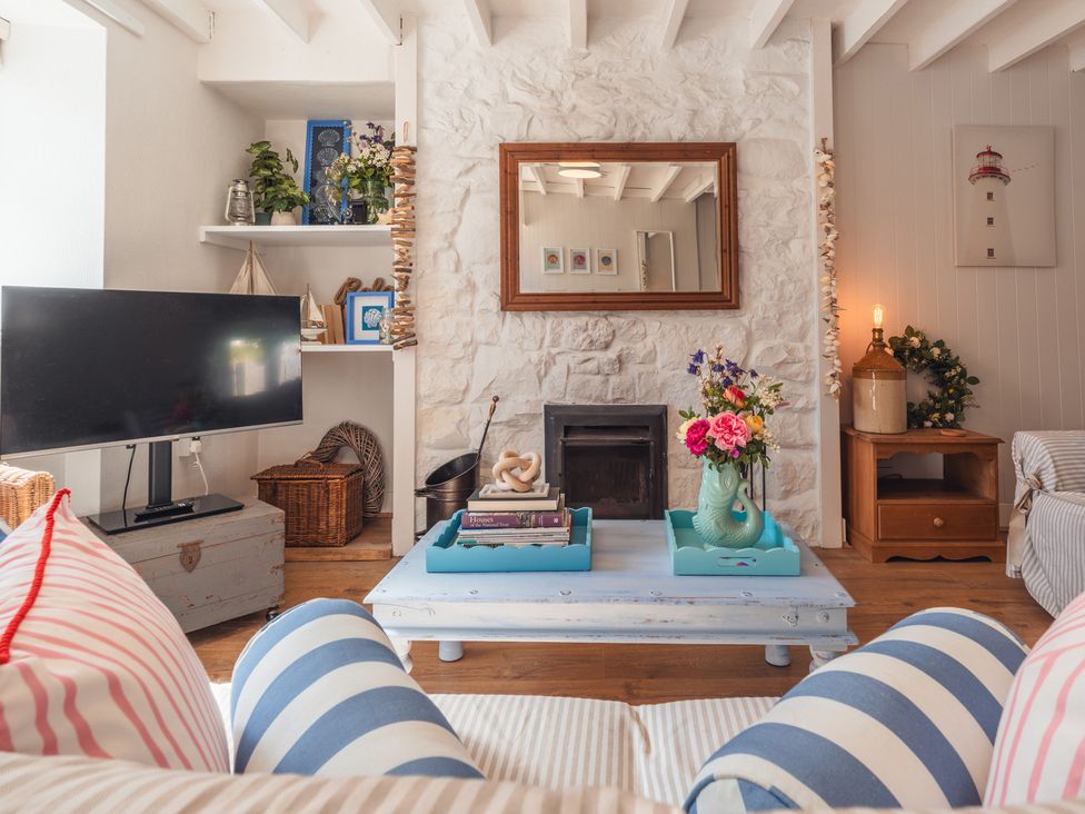 A living room with a coffee table and a television at Gerallt in Morfa Nefyn
