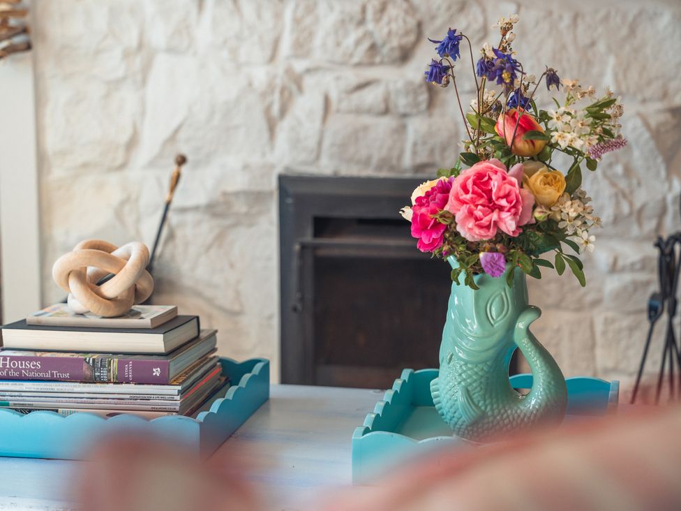 A living room with a vase of flowers and a stack of books at Gerallt in Morfa Nefyn