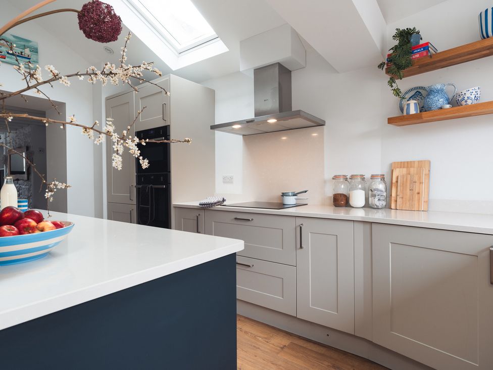 A kitchen with a kitchen island and bowl of apples at Gerallt in Morfa Nefyn