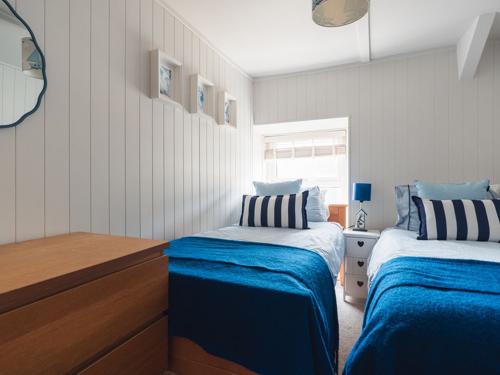 A bedroom with two beds and a dresser at Gerallt in Morfa Nefyn