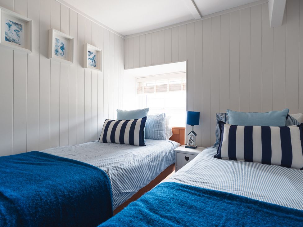 A bedroom with two beds and a nightstand at Gerallt in Morfa Nefyn