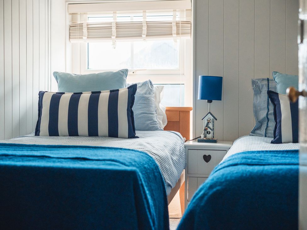 A bedroom with twin beds, lamps and window at Gerallt in Morfa Nefyn