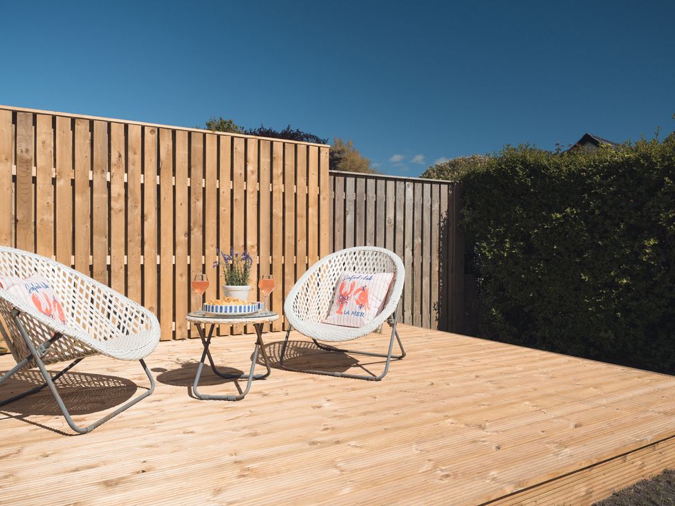 A garden with chairs and a table on a deck at Gerallt in Morfa Nefyn
