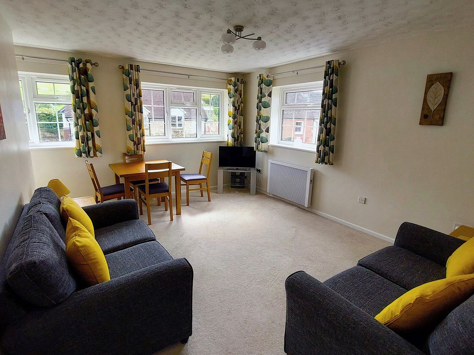 A living room with sofas, a table and a television at West Lulworth Apartment in West Lulworth