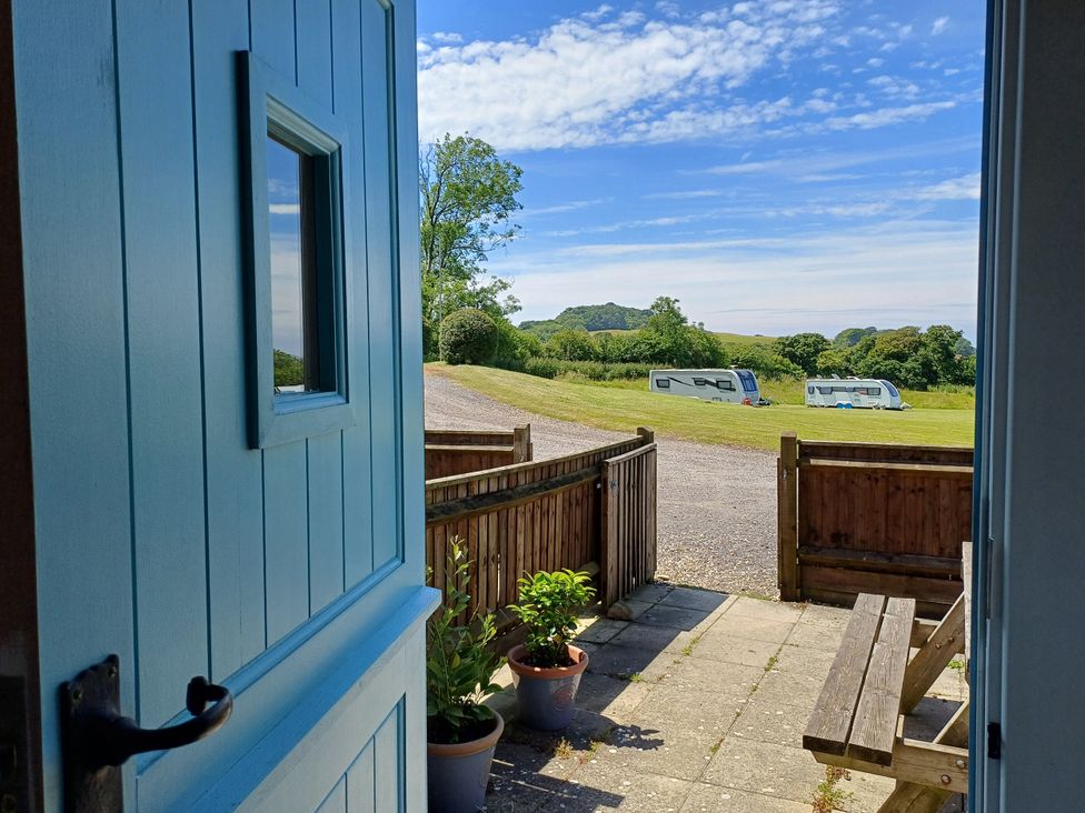 A view from a blue door showing trees and caravans outside at The Linhay in Bridport