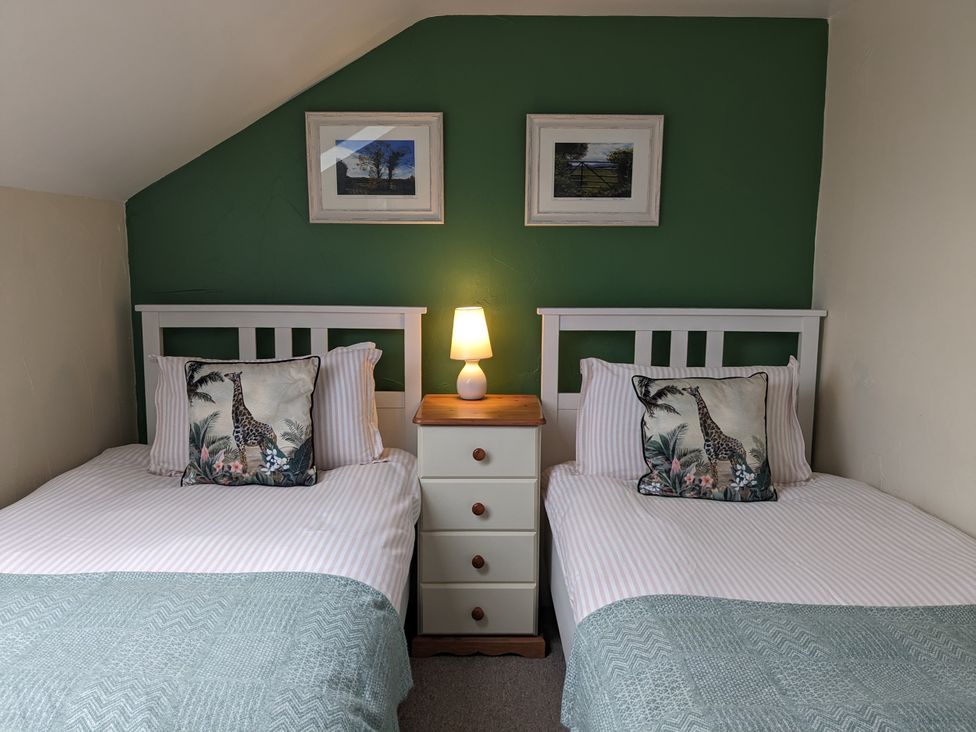 A bedroom with two beds and a lamp at The Linhay in Bridport