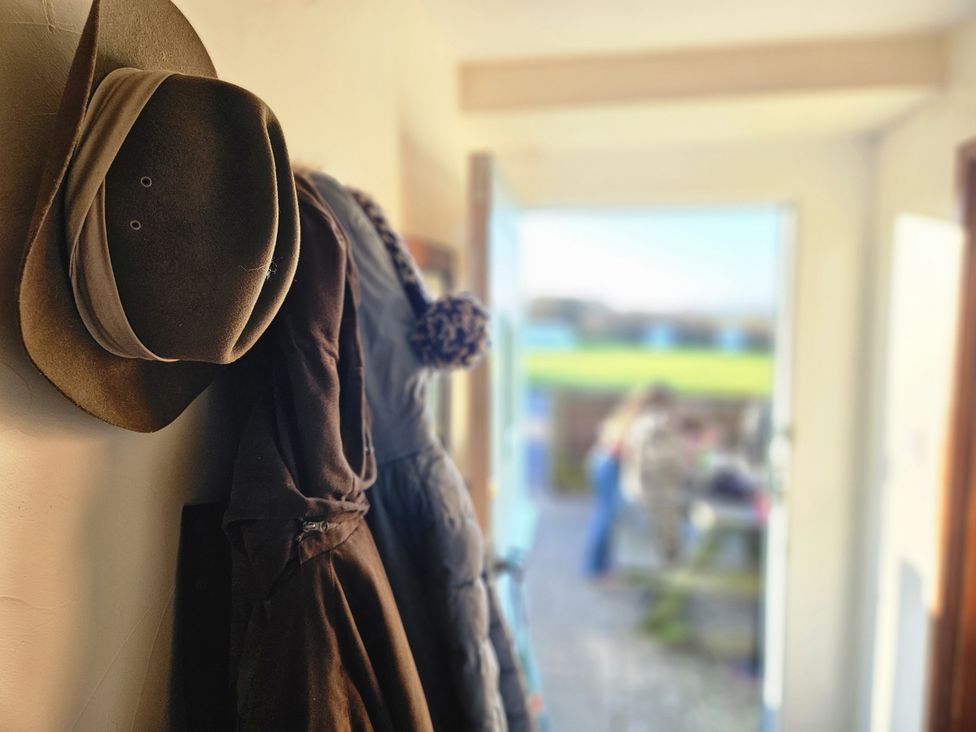 An entrance hall with a hat and coat on a rack at The Linhay in Bridport