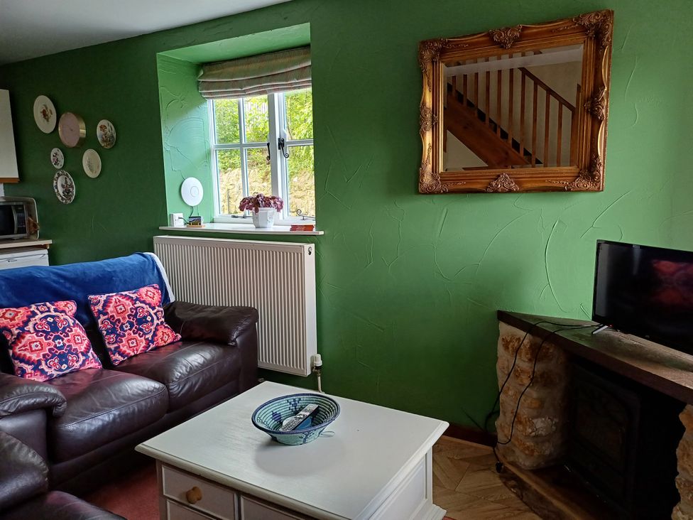 A living room with a sofa and a mirror at Barton Cottage in Bridport