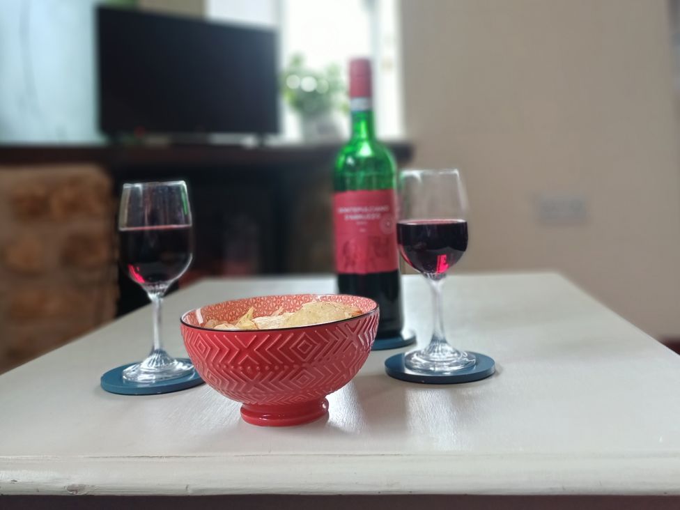 A wine bottle with two wine glasses and a bowl of chips at Barton Cottage in Bridport