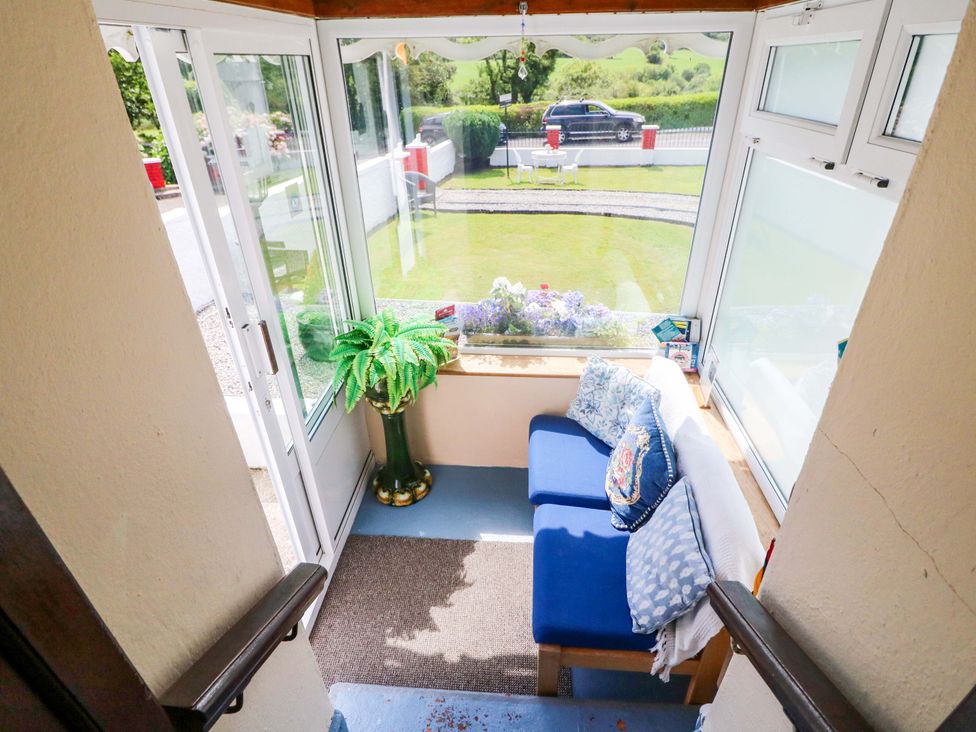 A conservatory with a sofa and potted plant at Waterfall House in Dunmanway, County Cork