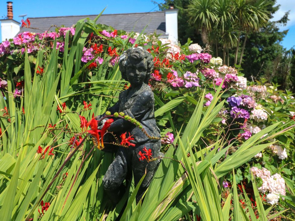 A statue surrounded by flowers in a garden at Waterfall House in Dunmanway, County Cork