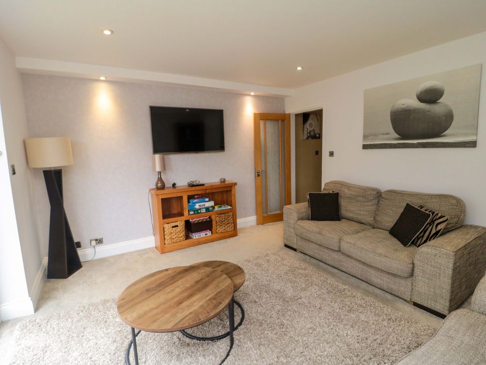 A living room with a sofa, coffee table, and television at Wyvill House in Cayton