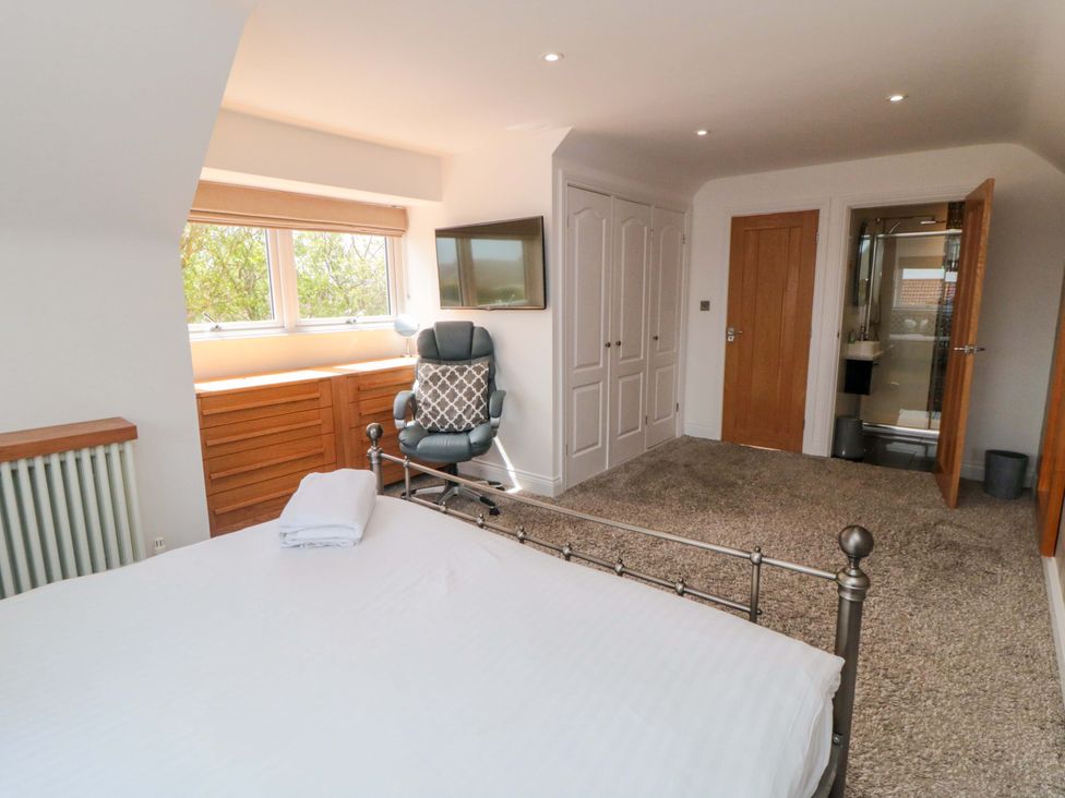 A bedroom with a bed, television, and en-suite bathroom at Wyvill House in Cayton