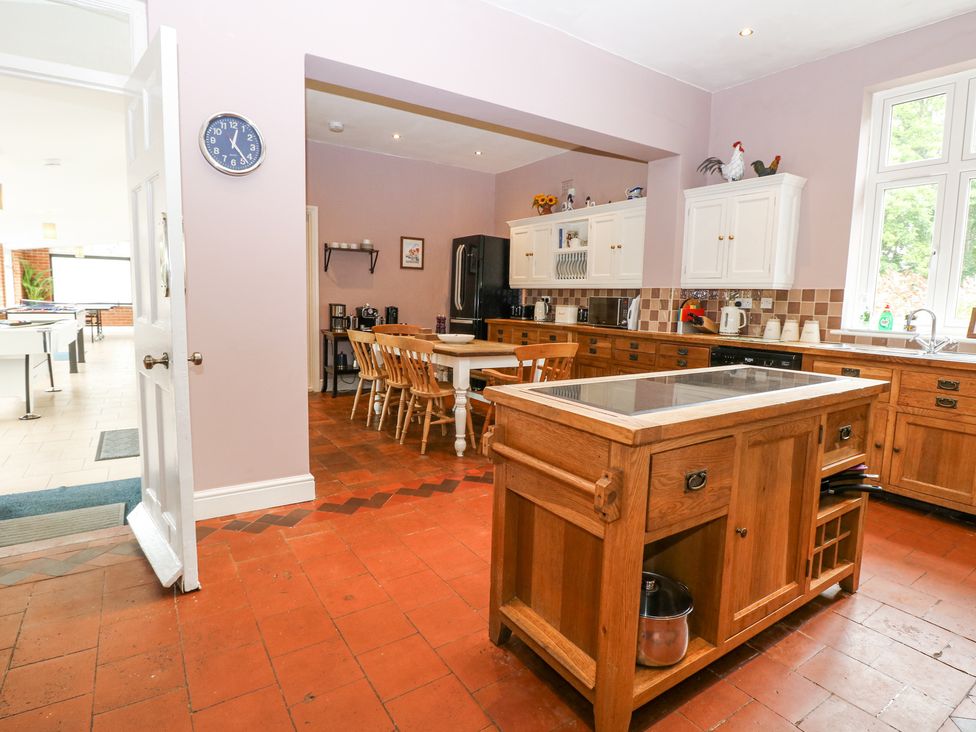 A kitchen with wooden cabinets a kitchen island and a dining table with chairs at High House in Southrepps