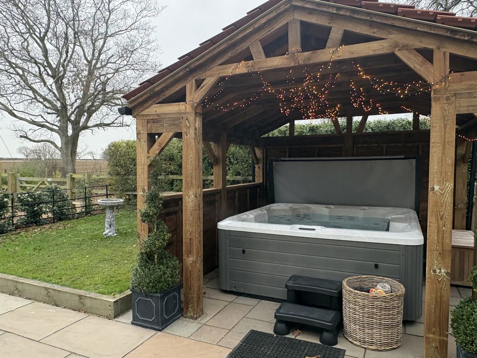 A hot tub under a canopy in a garden at High House in Southrepps