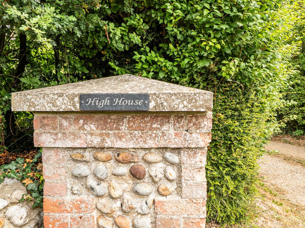 A house sign on a brick pillar surrounded by greenery at High House in Southrepps