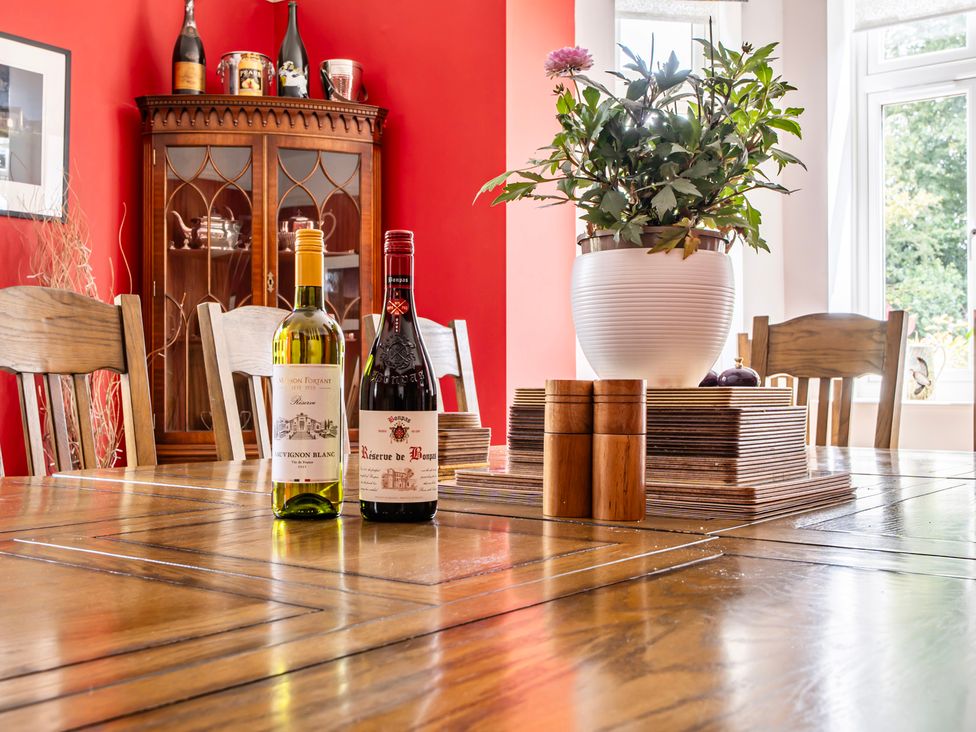 A dining room table with wine bottles and a plant at High House in Southrepps