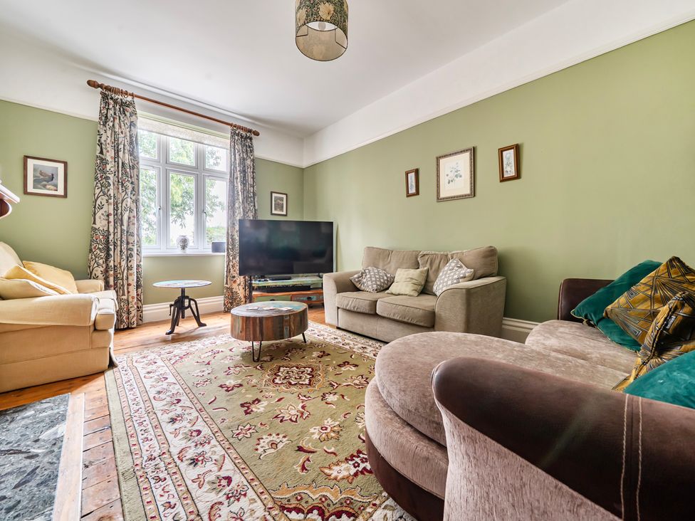 A living room with a sofa facing a television at High House in Southrepps