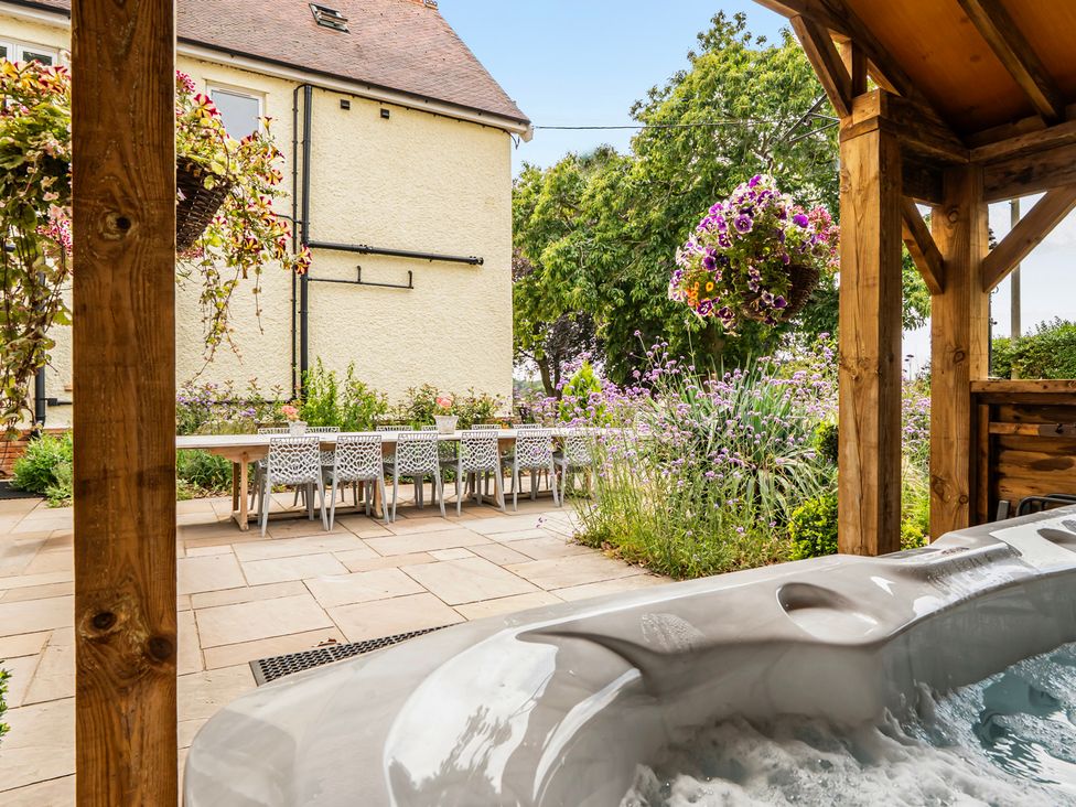 A garden with a hot tub and outdoor dining area at High House in Southrepps