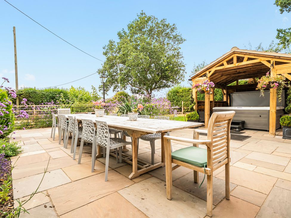 A garden with a table and chairs under a gazebo at High House in Southrepps