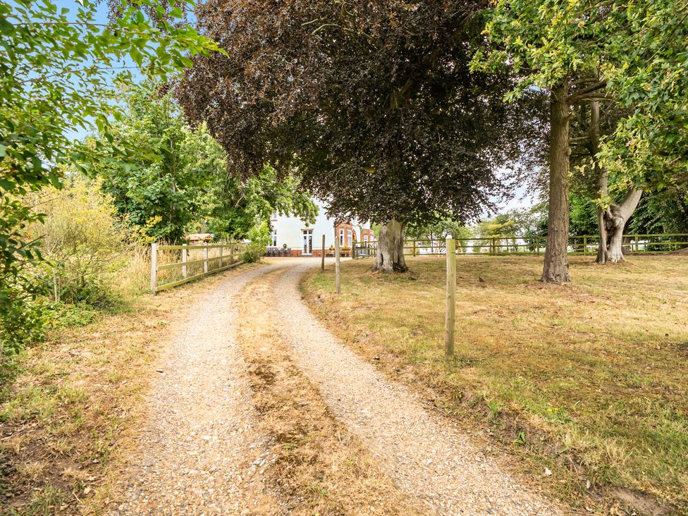 A gravel path leading to a house with trees and a fence at High House in Southrepps