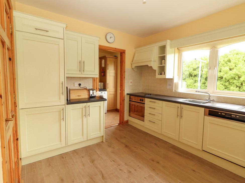 A kitchen with cabinets and appliances at 29 Church Field in Doonbeg, County Clare