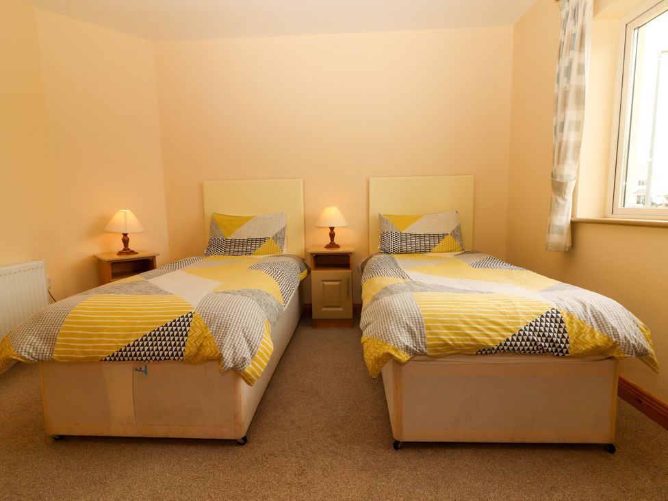 A bedroom with two beds and bedside tables at 29 Church Field in Doonbeg, County Clare