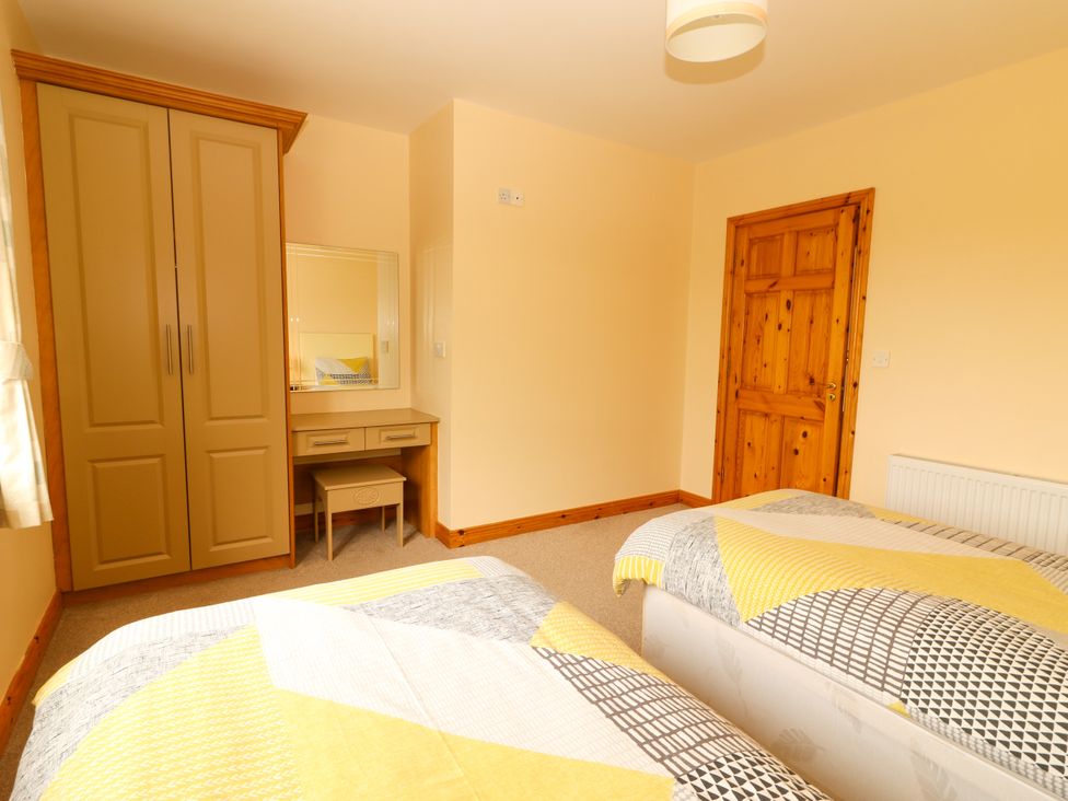 A bedroom with two beds and a wardrobe at 29 Church Field in Doonbeg, County Clare