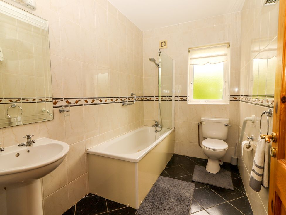 A bathroom with a bathtub, sink, shower, and toilet at 29 Church Field in Doonbeg, County Clare