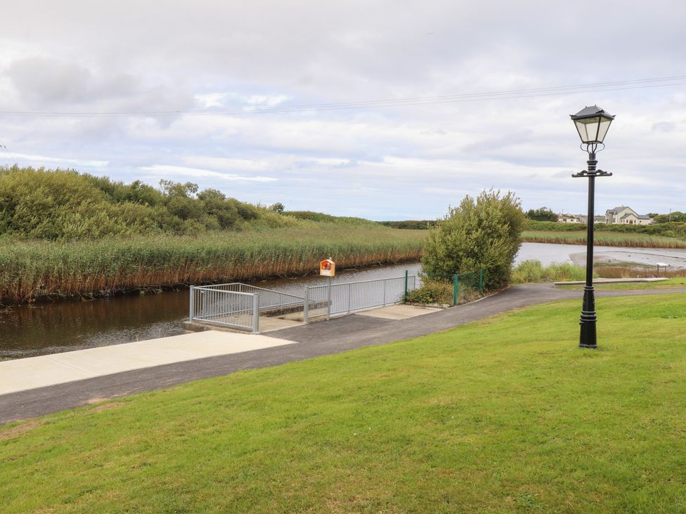 A pathway leading to a river with reeds and a lamp post at 29 Church Field in Doonbeg, County Clare