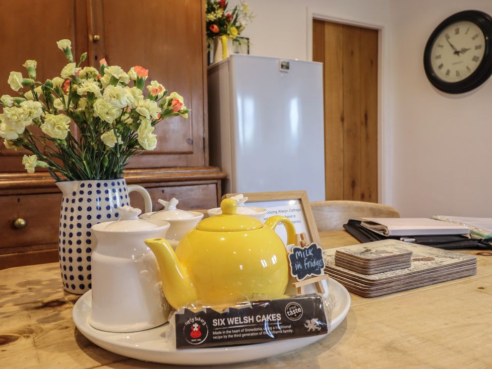 A kitchen with a yellow teapot and flowers on the table at Alwyn Cottage in Froncysyllte