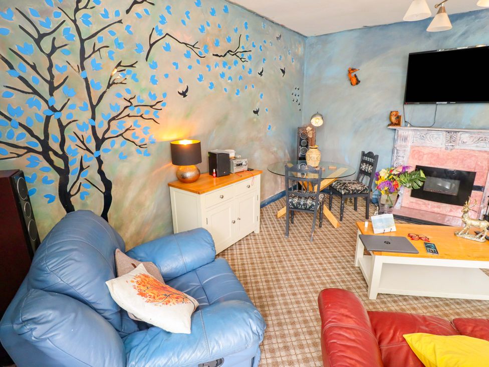 A living room with a sofa, table, and decorations at Peartree Cottage 