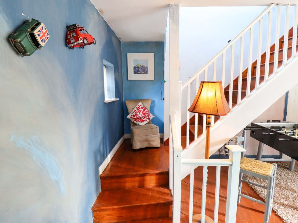 A hallway with a chair and lamp at Peartree Cottage