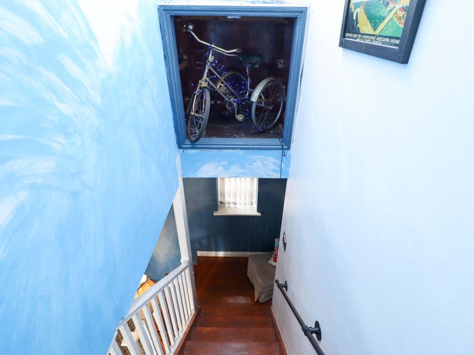 A staircase with a bicycle in a window at Peartree Cottage