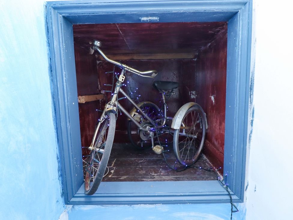A bicycle in a storage space with decorative lights at Peartree Cottage
