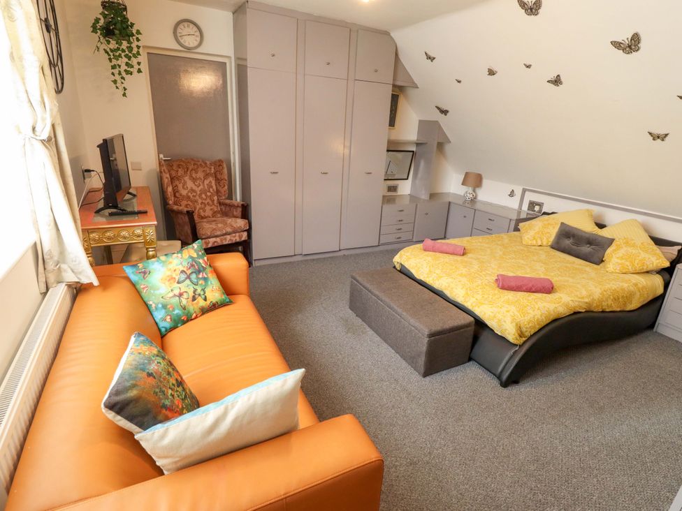 A bedroom with a bed, sofa, and armchair at Peartree Cottage