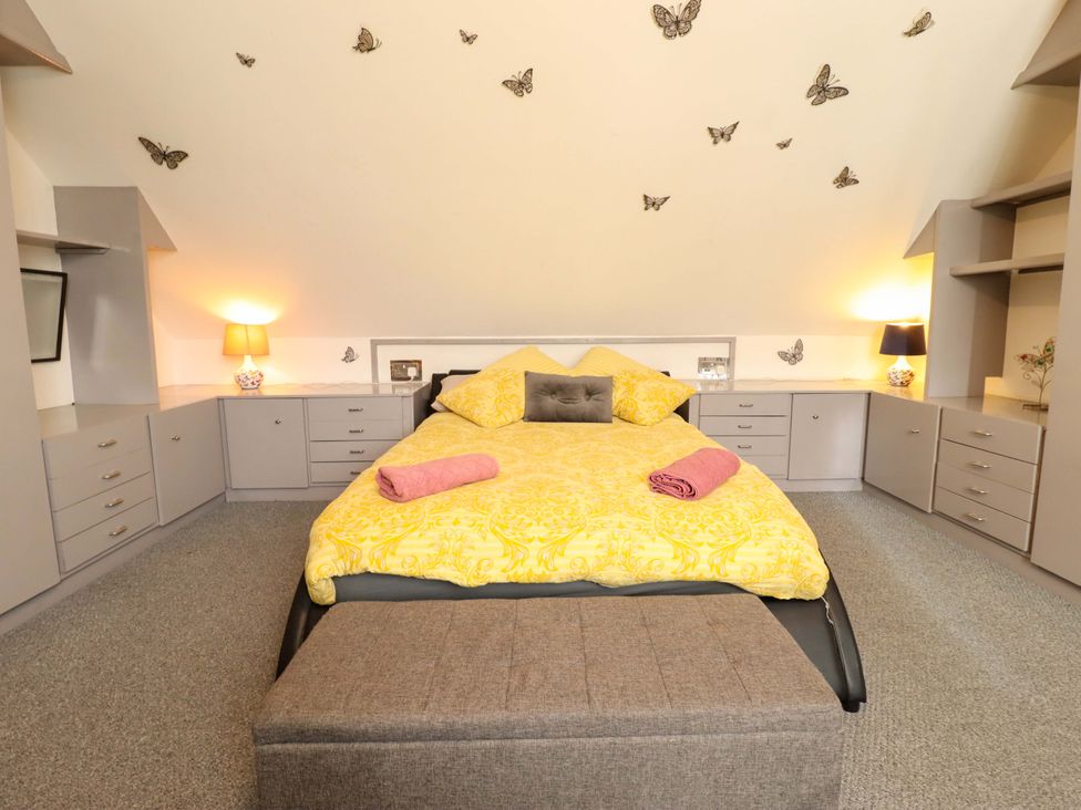 A bedroom with a bed and storage cabinets at Peartree Cottage