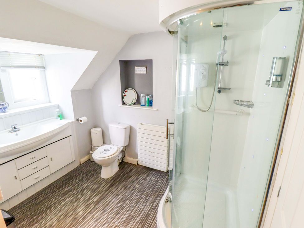 A bathroom with a shower, toilet, sink and mirror at Peartree Cottage