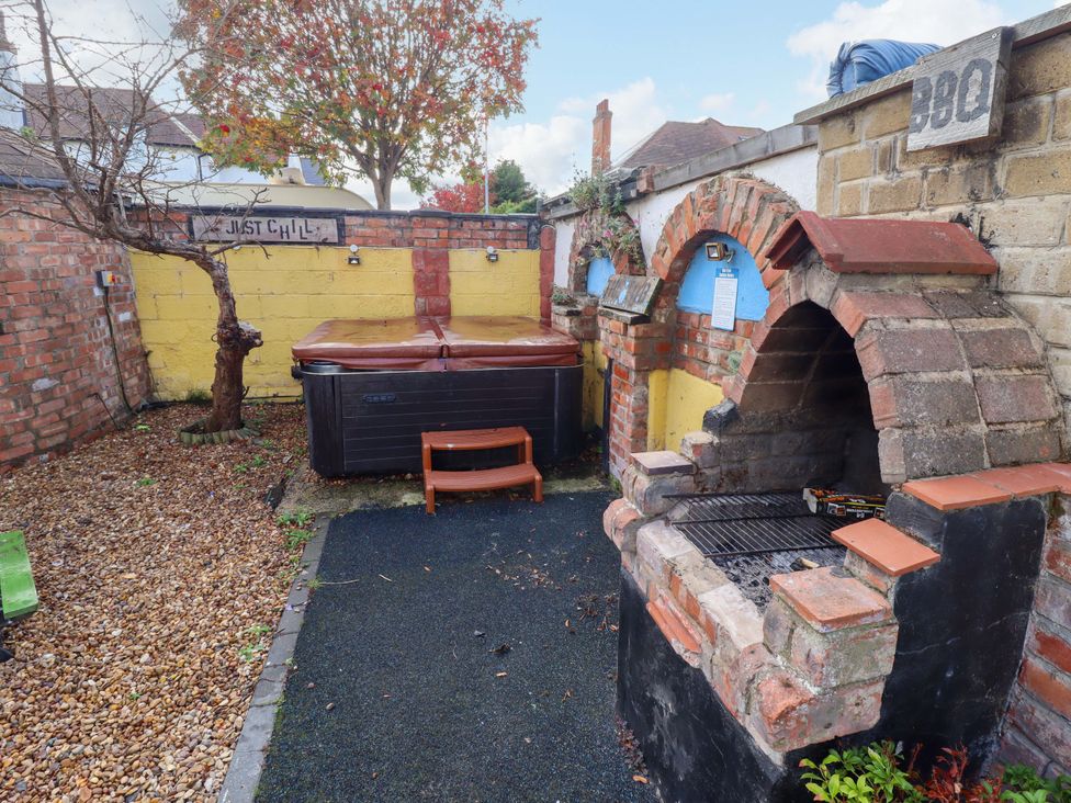 A garden with a hot tub and outdoor grill at Peartree Cottage