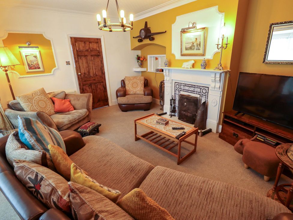 A living room with a sofa, armchair, coffee table and television at Telford Lodge Skegness