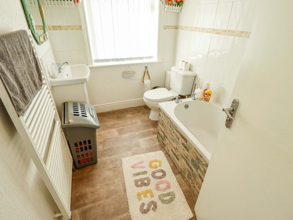 A bathroom with a bath, toilet, sink, and towel radiator at Telford Lodge in Skegness