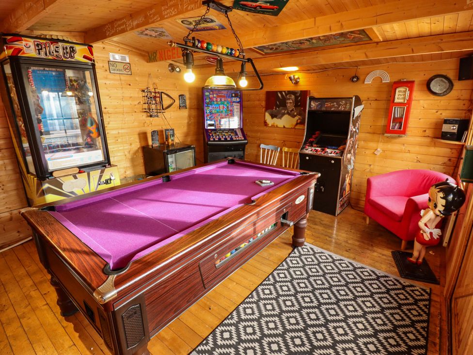 A games room with a pool table and arcade machines at Telford Lodge in Skegness