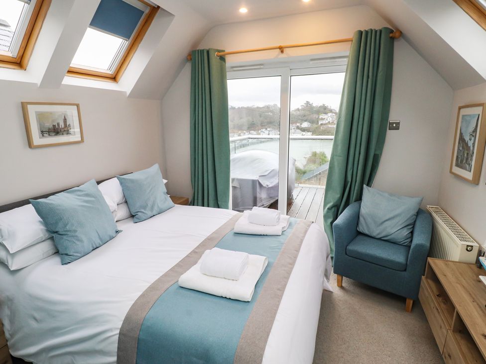 A bedroom with a bed and a chair at Alltwen in Borth-y-Gest